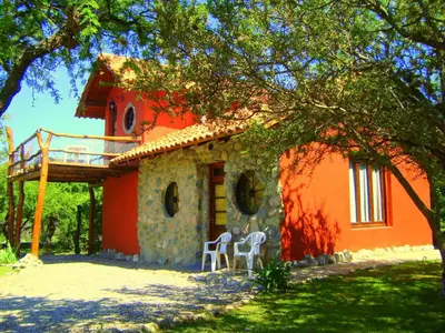 a house with two white chairs in front of it at Cabañas en Piedras Maia in Merlo