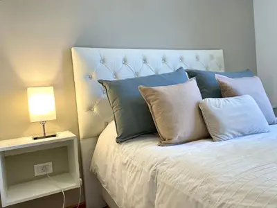 a bed with blue and white pillows and a lamp at Balcarce Deluxe in Cordoba