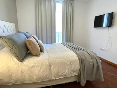a bedroom with a bed with pillows and a television at Balcarce Deluxe in Cordoba