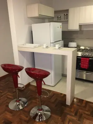 a kitchen with a white counter and red stools at Balcarce Deluxe in Cordoba