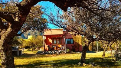 a small red house with a tree in front of it at Cabañas Chacras del Arroyo Vidal in Carpintería