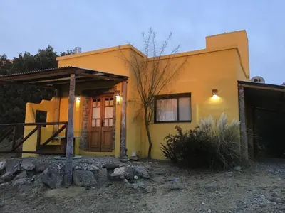 a small yellow house with a front door at Cabañas Chacras del Arroyo Vidal in Carpintería