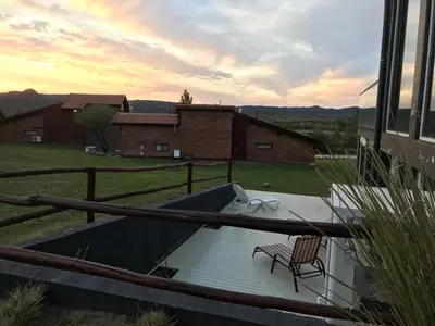 a deck with two chairs and a table and a building at Brisas de Nono in Nono