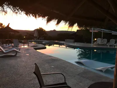 a swimming pool with chairs and a table with a sunset at Brisas de Nono in Nono