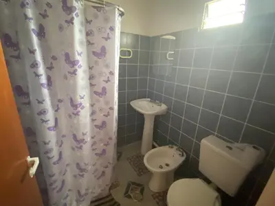 a bathroom with a toilet and a sink and a shower curtain at Cabañas la soñada de T in Tanti