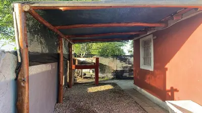 a red building with a blue roof and a porch at Cabañas la soñada de T in Tanti