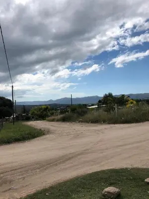 an empty dirt road with a cloudy sky at Cabañas la soñada de T in Tanti