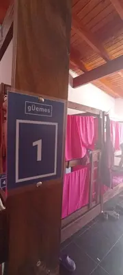 a clock on a pole in a room with pink clothes at Güemes Hostel Cordoba in Cordoba