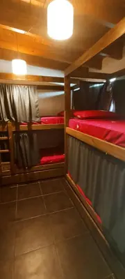 a room with two bunk beds with red sheets at Güemes Hostel Cordoba in Cordoba