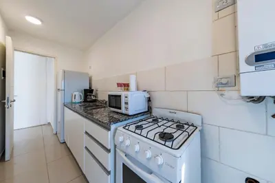 a white kitchen with a stove and a microwave at Un Rinconcito en Guemes - Confort y Calidez in Cordoba