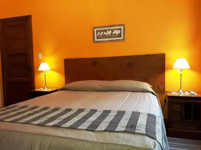 a bedroom with a bed with orange walls and two lamps at El Potrerillo Posada in Santa Rosa de Calamuchita