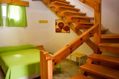 a room with a green bed and wooden stairs at Casitas de Norma in Embalse
