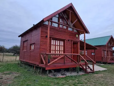 a large red house with a gambrel roof at Cabaña en Los Reartes in Villa General Belgrano