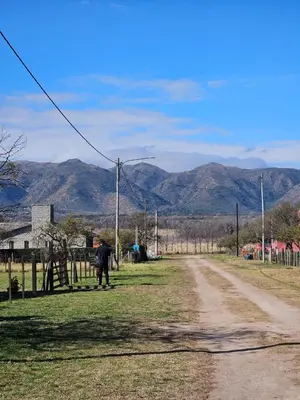 a person walking down a dirt road with mountains in the background at Cabaña en Los Reartes in Villa General Belgrano