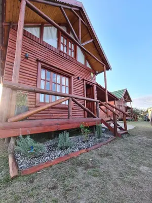 a log cabin with a porch and a yard at Cabaña en Los Reartes in Villa General Belgrano