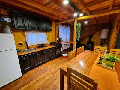 a kitchen with a white refrigerator and a wooden floor at Cabaña en Los Reartes in Villa General Belgrano