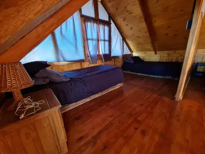 a bedroom with two beds in a wooden cabin at Cabaña en Los Reartes in Villa General Belgrano
