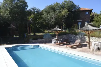 a swimming pool with chairs and tables and umbrellas at Cabañas Bosque Encantado in Merlo