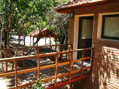 a brick house with a wooden deck next to a building at Cabañas Bosque Encantado in Merlo