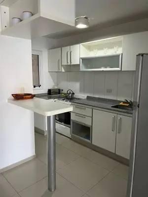 a kitchen with white cabinets and a white counter top at Departamento Skala in Cordoba