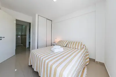 a white room with a bed with a striped blanket at 24 de Septiembre 1859 B Gral Paz in Cordoba
