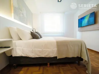 a bedroom with a bed with white sheets and a window at SERIETÁ Frente al PARQUE SARMIENTO in Cordoba