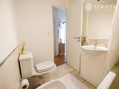 a white bathroom with a toilet and a sink at SERIETÁ Frente al PARQUE SARMIENTO in Cordoba