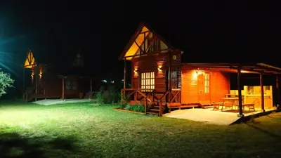 a wooden cabin with a table in the yard at night at Cabañas en los reartes in Los Reartes