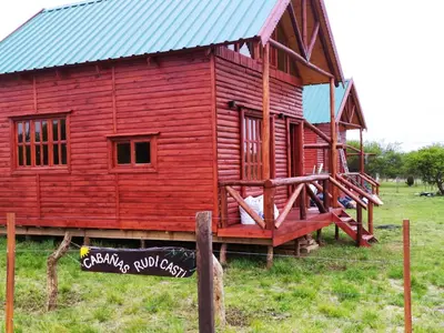 a red house with a blue roof in a field at Cabañas en los reartes in Los Reartes