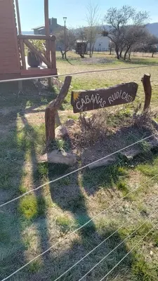 a sign sitting on the grass next to a fence at Cabañas en los reartes in Los Reartes