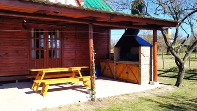 a wooden cabin with a bench and a stove at Cabañas en los reartes in Los Reartes