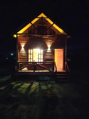 a log cabin with a red door at night at Cabañas en los reartes in Los Reartes