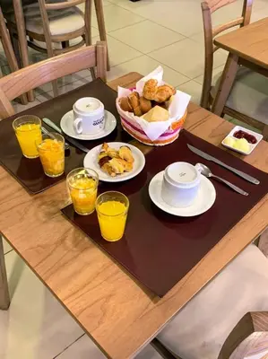 a table with plates of food and glasses of orange juice at Hotel Sialdorf in Villa Carlos Paz