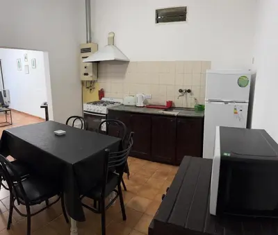a kitchen with a table and a white refrigerator at Casa zona CUCÚ de 2 dormitorios in Villa Carlos Paz