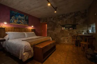 a bedroom with a bed and a stone wall at Puesto Victoria - Adults only in Yacanto