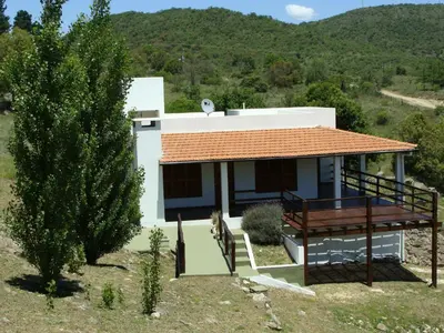 a white house with a red roof and a tree at Vista del Condor in Villa Ciudad de America