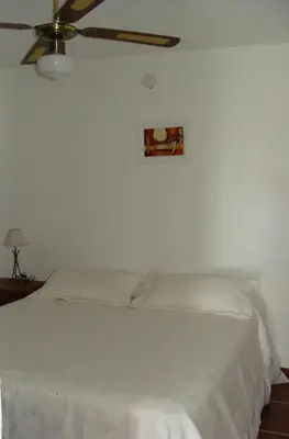 a bedroom with a white bed with a ceiling fan at Vista del Condor in Villa Ciudad de America