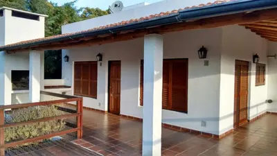 a white house with wooden doors and a porch at Vista del Condor in Villa Ciudad de America