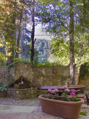 a picnic table in a garden with a stone wall and flowers at Cabañas Tá Péfka in La Cumbrecita