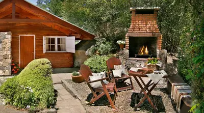 a patio with a fireplace and a table and chairs at Cabañas Tá Péfka in La Cumbrecita