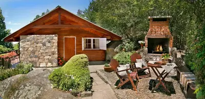 a log cabin with a fireplace and a table and chairs at Cabañas Tá Péfka in La Cumbrecita