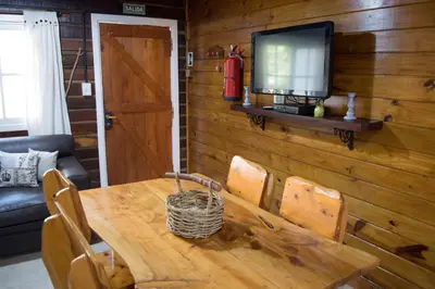 a wooden dining room table with a television on a wall at Cabañas Tá Péfka in La Cumbrecita