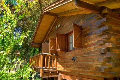 a log cabin with a porch and a window at Cabañas Tá Péfka in La Cumbrecita