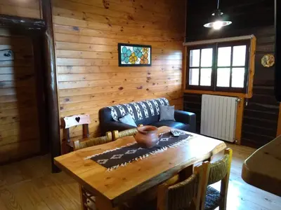 a living room with a wooden table and a couch at Cabañas Tá Péfka in La Cumbrecita