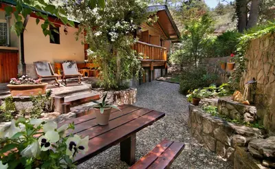 a patio with a wooden table and benches in a yard at Cabañas Tá Péfka in La Cumbrecita
