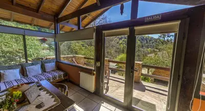 a room with a couch and a table and glass doors at Cabañas Tá Péfka in La Cumbrecita