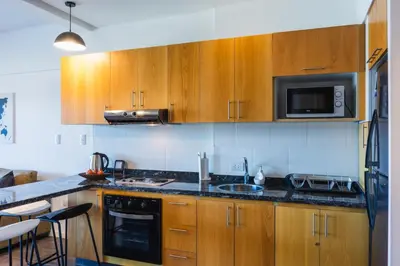 a kitchen with wooden cabinets and a sink and a microwave at Depto - Lago los Molinos in Potrero de Garay
