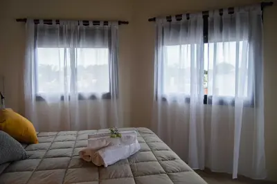 a bedroom with white curtains and a bed with towels on it at Complejo Moras I in Almafuerte