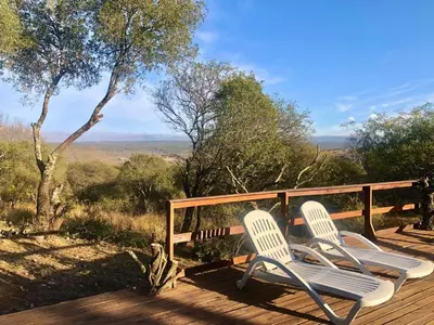 two chairs sitting on a wooden deck with a view at Cabaña EL GALLO in Villa General Belgrano