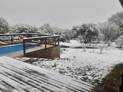a snow covered yard with a swimming pool and a bridge at Cabaña EL GALLO in Villa General Belgrano